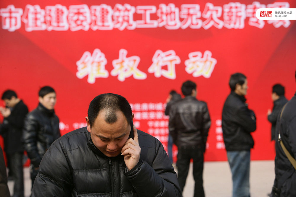 2013年1月27日，宁波市住建委“建筑工地无欠薪专项维权行动”在宁波书城外广场举行，20余家大型建筑企业负责人现场办公，对讨薪工人涉及的问题现场进行解答，确保工人及时拿到工钱，开心回家过春节。图为一位工人在打电话。张培坚/视觉中国